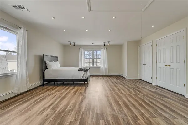 a spacious bedroom with a bed and wooden floor