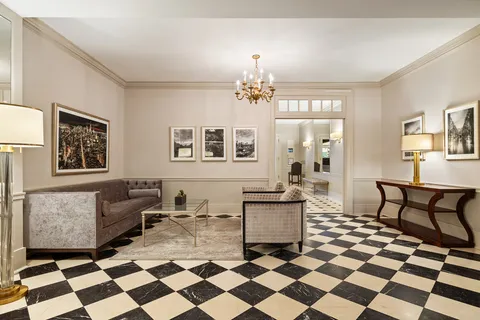 a living room with a black white checkered floor with a gaming machine and dining chairs