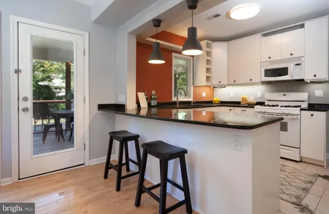 a kitchen with stainless steel appliances granite countertop a table chairs sink and cabinets