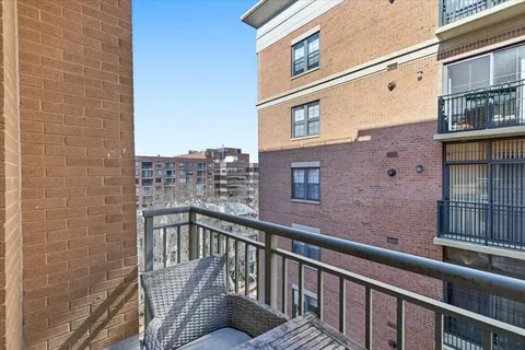 a view of balcony with a couple of cars parked in front of a building