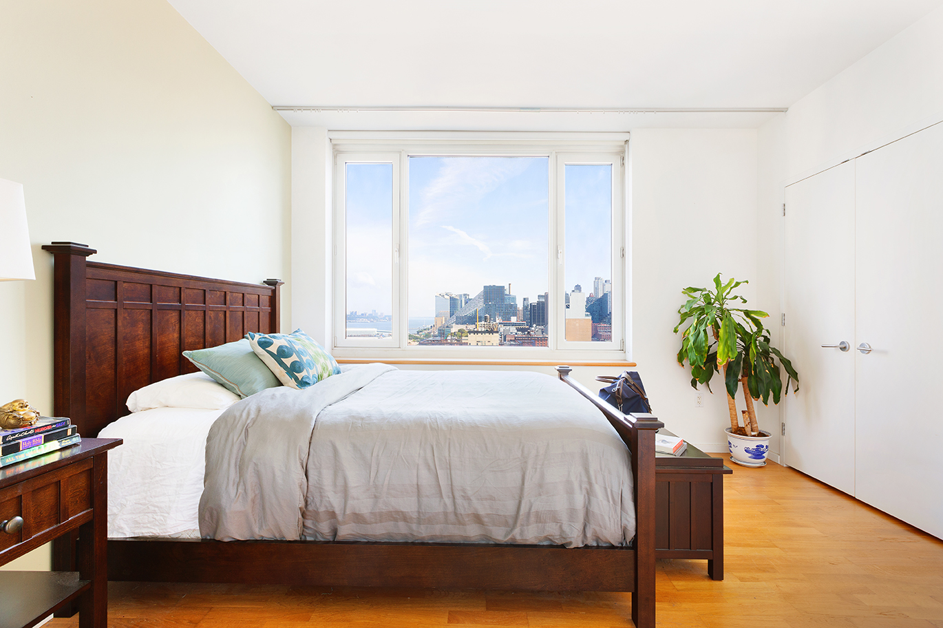 635 West 42nd Street, Unit 17D Manhattan, NY 10036 - Photo 3 of 6 a bedroom with a bed table and a potted plant