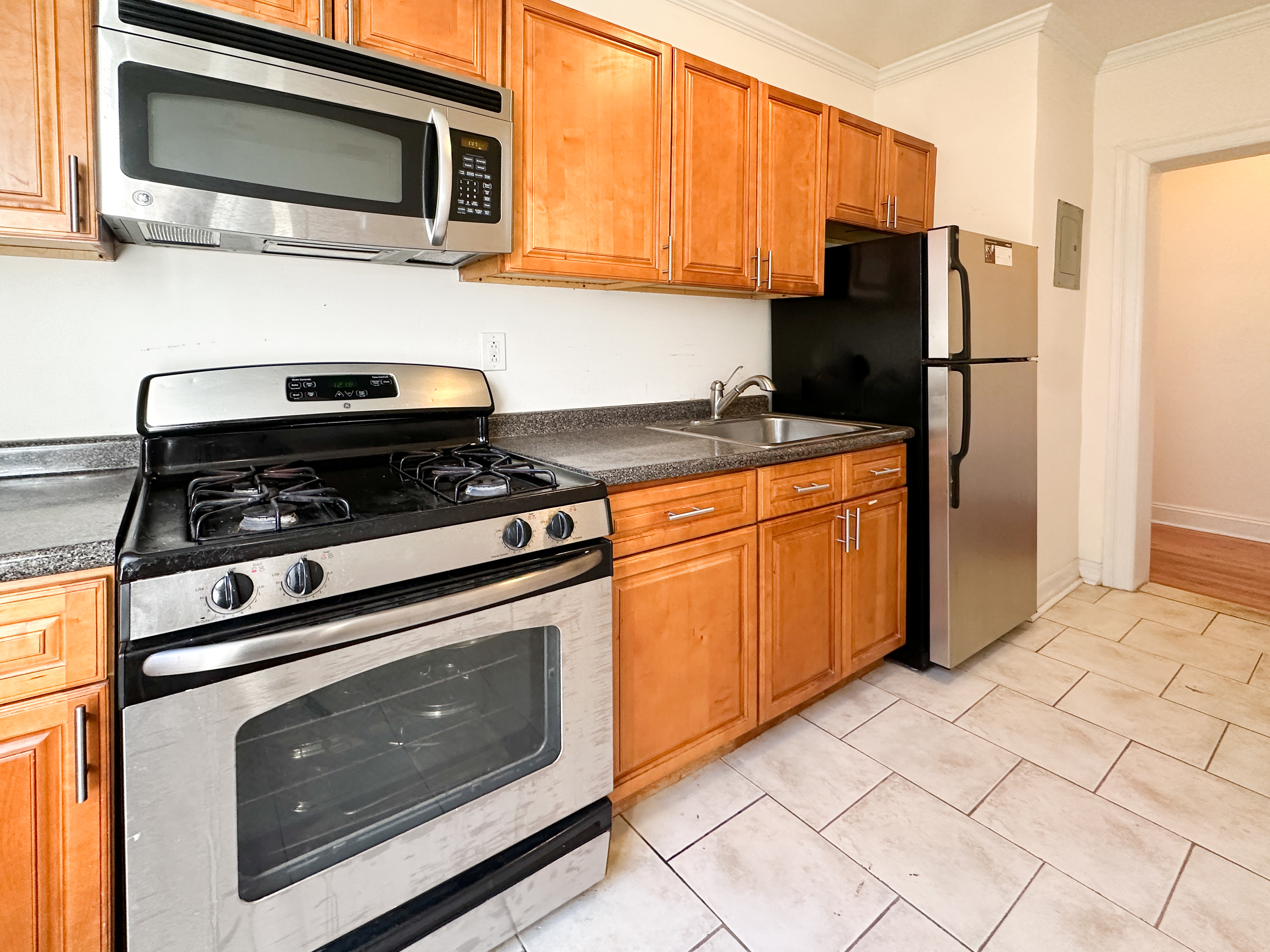 1506 Overing Street, Unit 1D Bronx, NY 10461 - Photo 8 of 10 a kitchen with stainless steel appliances granite countertop a stove microwave and refrigerator
