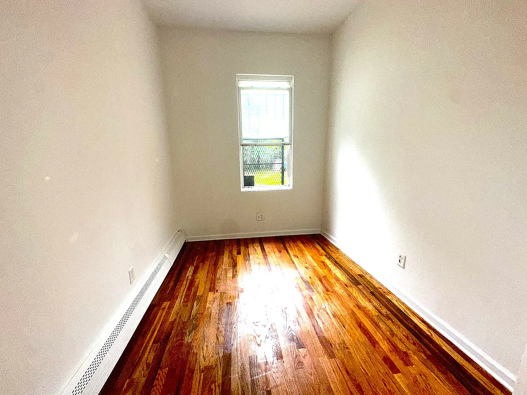918 Dekalb Avenue, Unit 1 Brooklyn, NY 11221 - Photo 4 of 11 an empty room with wooden floor and windows