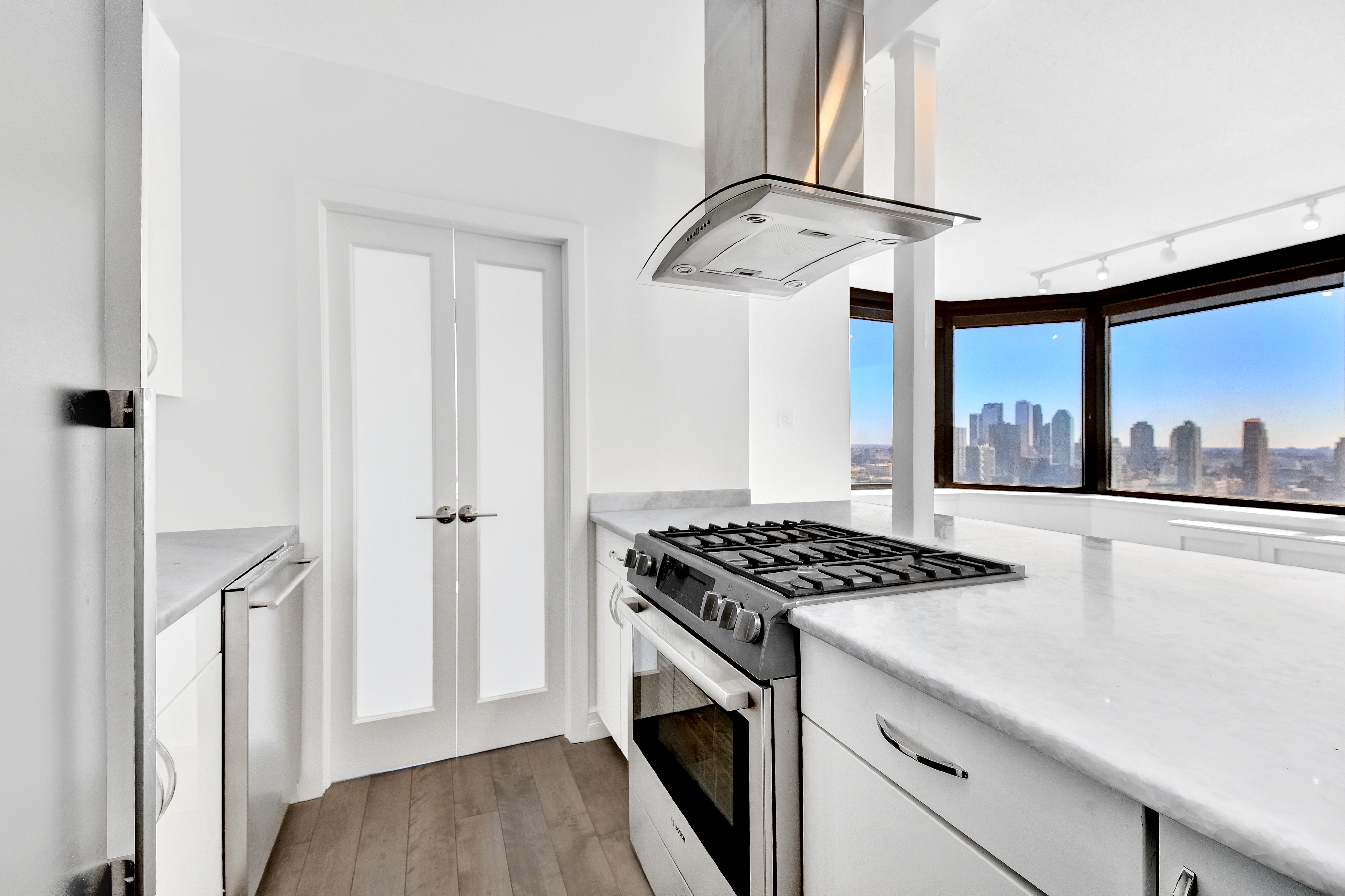 415 East 37th Street, Unit 32G Manhattan, NY 10016 - Photo 4 of 19 a kitchen with stainless steel appliances granite countertop a stove and a refrigerator with wooden floor