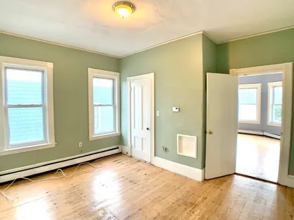 a view of an empty room with window and wooden floor