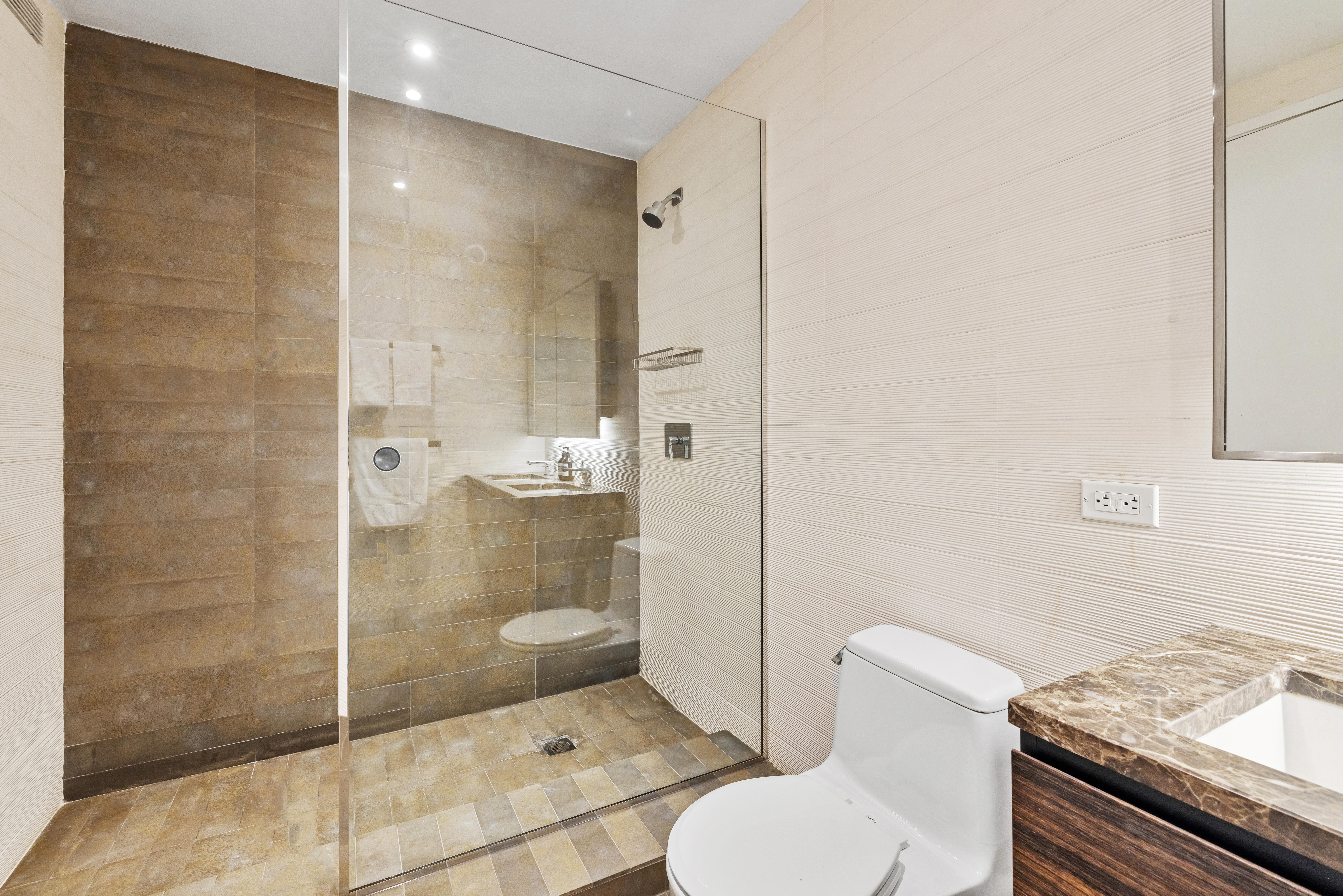 515 East 72nd Street, Unit 40E Manhattan, NY 10021 - Photo 13 of 34 a bathroom with a granite countertop toilet a sink and shower