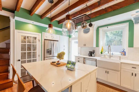 a kitchen with a sink a stove and white cabinets with wooden floor