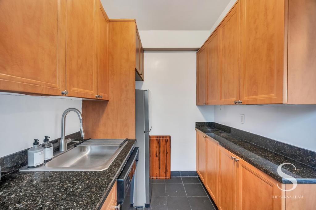 7 Lexington Avenue, Unit 5E Manhattan, NY 10010 - Photo 14 of 27 a kitchen with granite countertop a sink a stove and a wooden cabinets