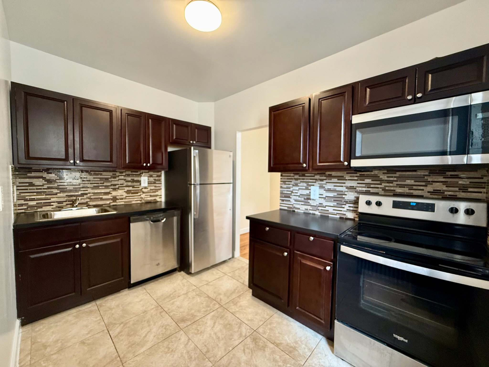 957 Greene Avenue, Unit BWEST Brooklyn, NY 11221 - Photo 5 of 8 a kitchen with granite countertop wooden cabinets and stainless steel appliances