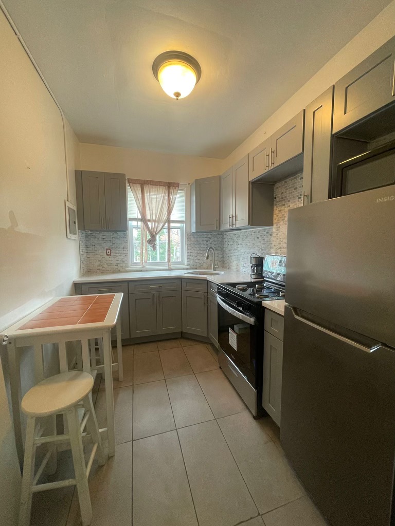 88-13 Corona Avenue, Unit 2 Queens, NY 11373 - Photo 2 of 7 a kitchen with a stove a sink and a refrigerator