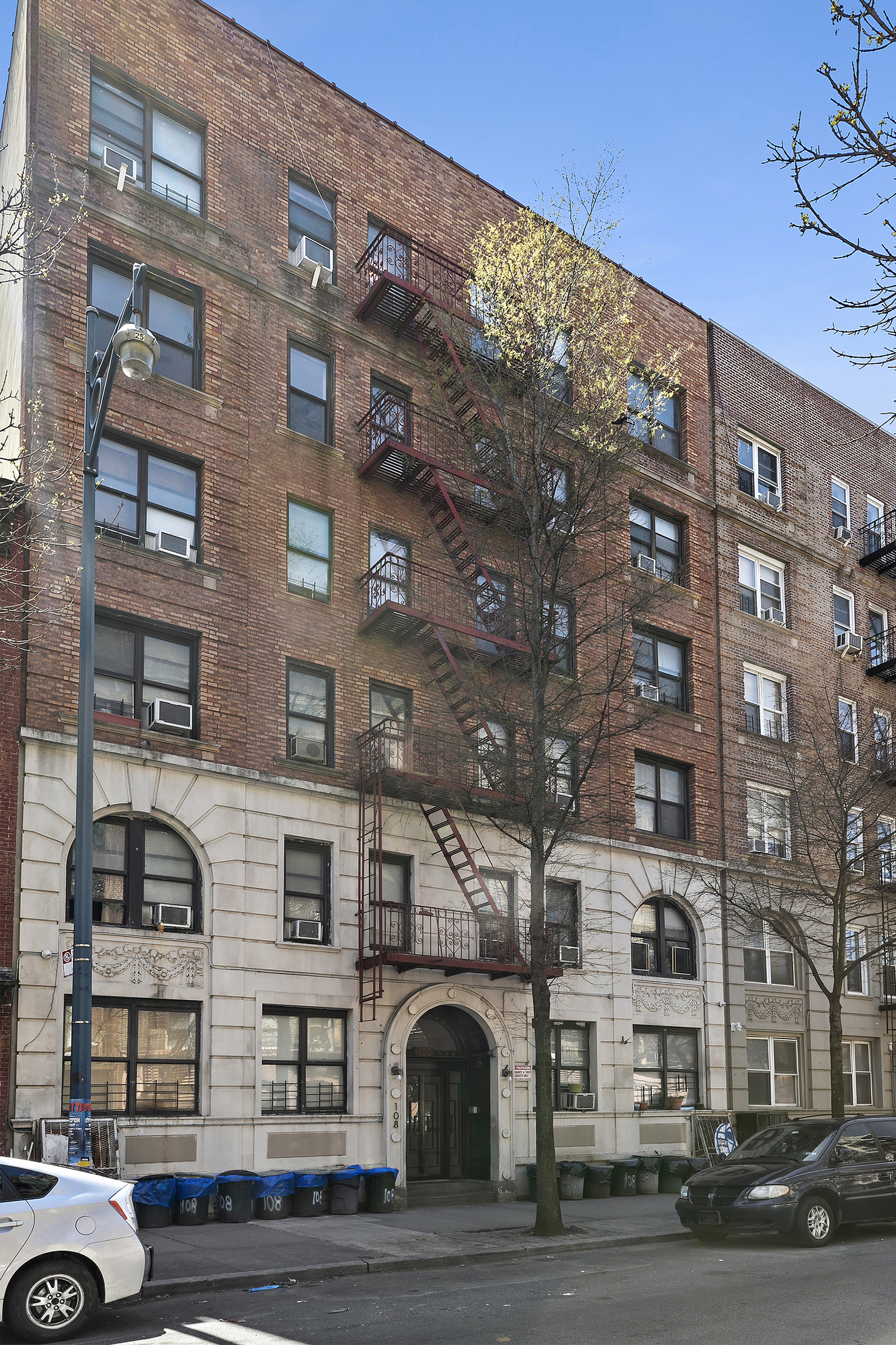 108 Division Avenue, Unit 22 Brooklyn, NY 11211 - Photo 10 of 11 a front view of a building with lot of cars and trees