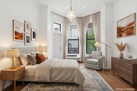 a bedroom with a bed couches and windows