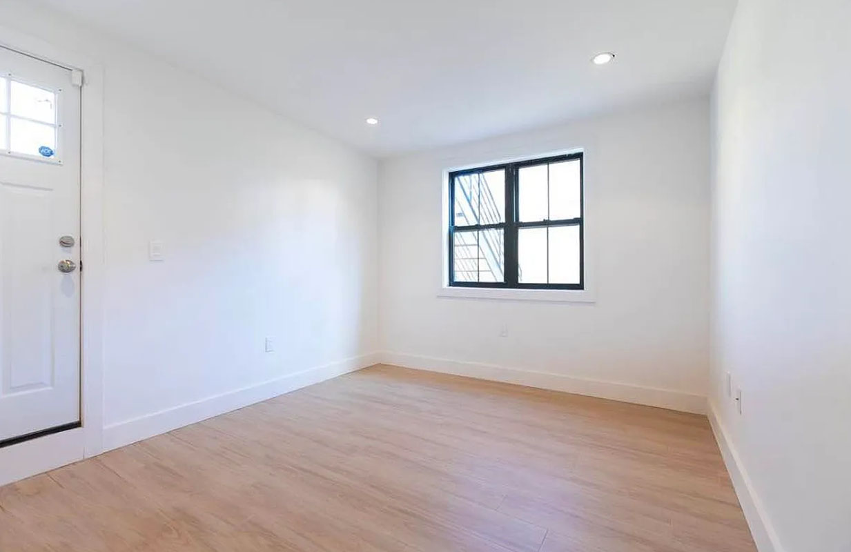 1128 Halsey Street, Unit 1 Brooklyn, NY 11207 - Photo 2 of 6 an empty room with wooden floor and windows