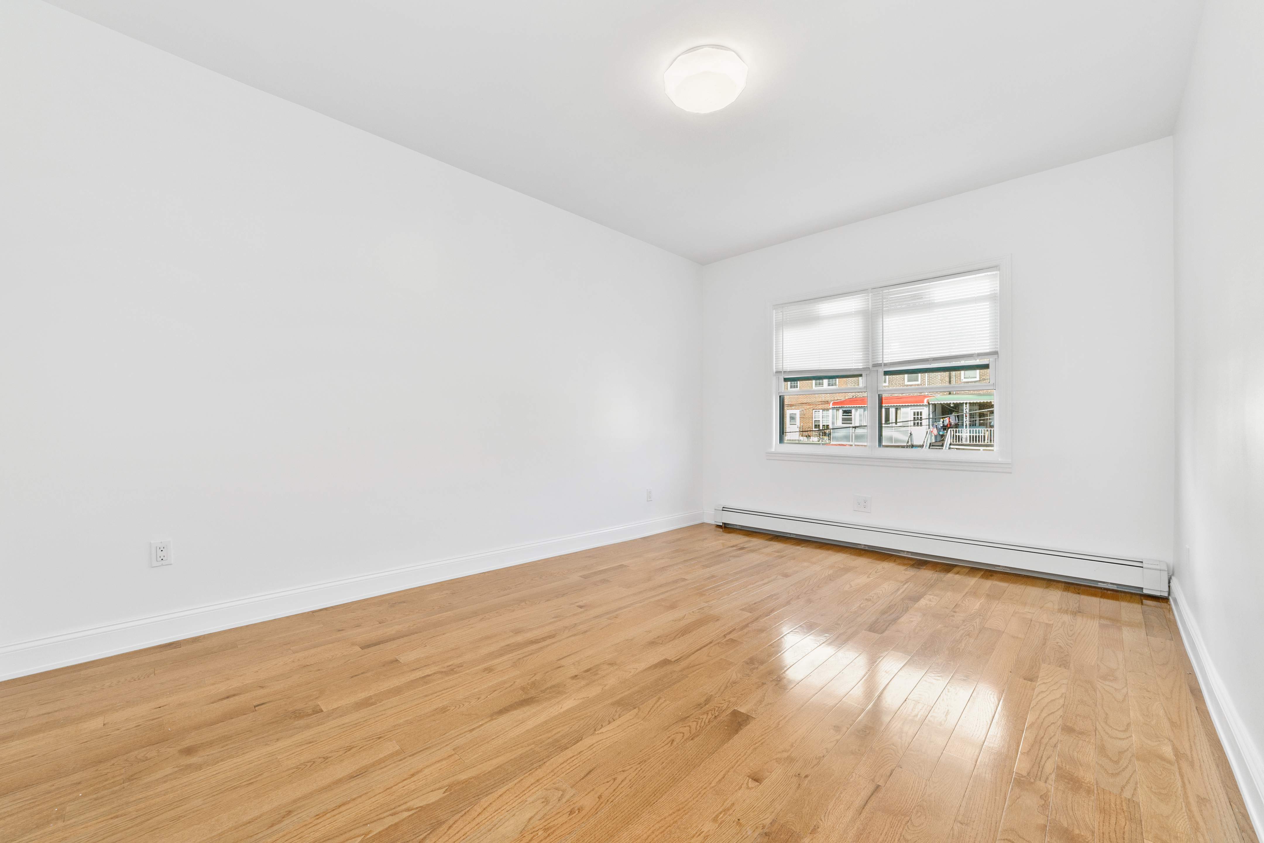 24-41 82nd Street Queens, NY 11370 - Photo 6 of 15 an empty room with wooden floor and windows