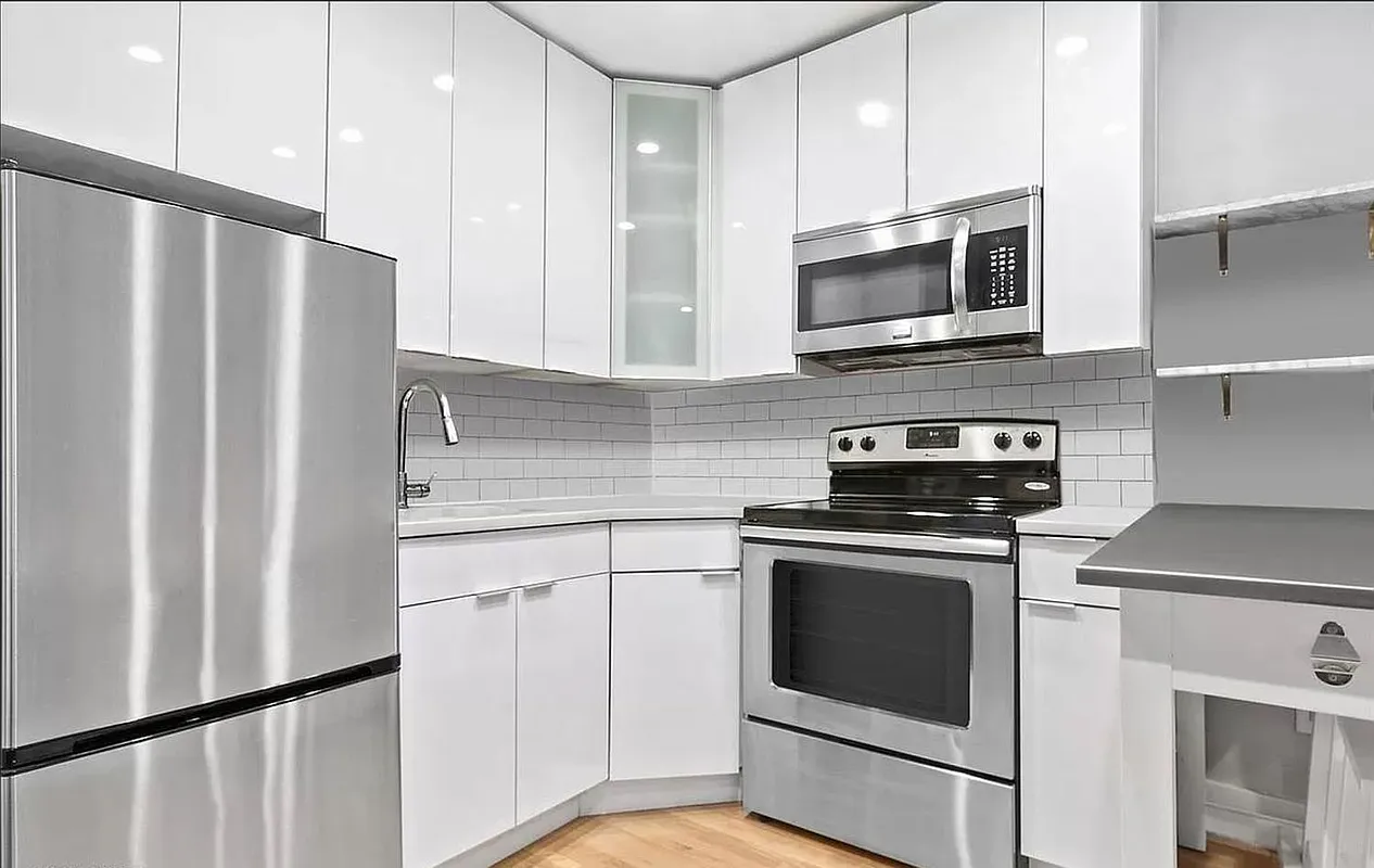 228 East 81st Street, Unit 7A Manhattan, NY 10028 - Photo 4 of 7 a kitchen with stainless steel appliances white cabinets white stove a microwave and a refrigerator