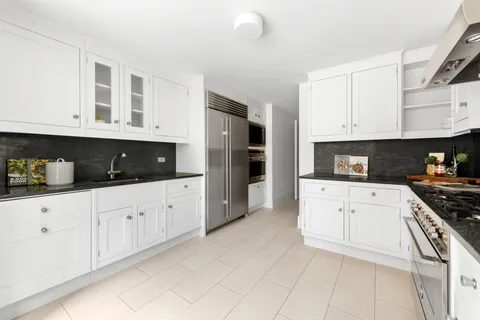a kitchen with stainless steel appliances granite countertop a stove a sink and white cabinets