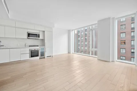 a view of an empty room with a kitchen and window