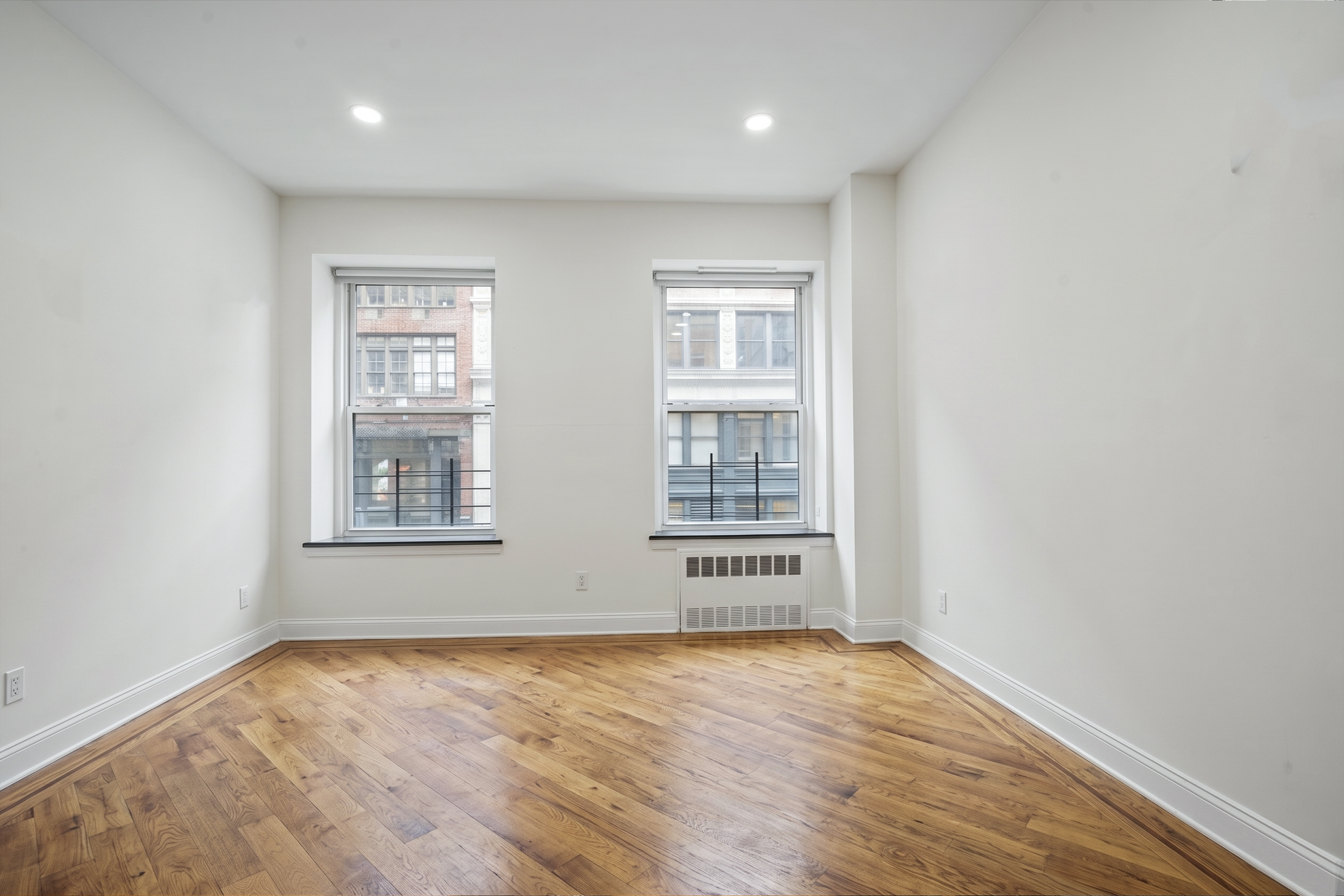 36 West 35th Street, Unit 2A Manhattan, NY 10001 - Photo 4 of 11 an empty room with wooden floor and windows