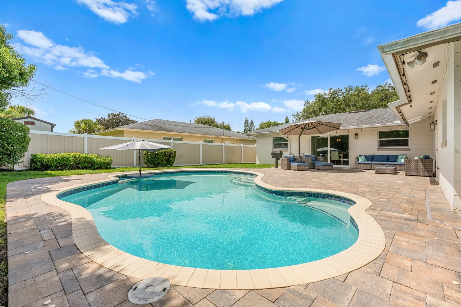 a view of a patio with couches and table and chairs under an umbrella