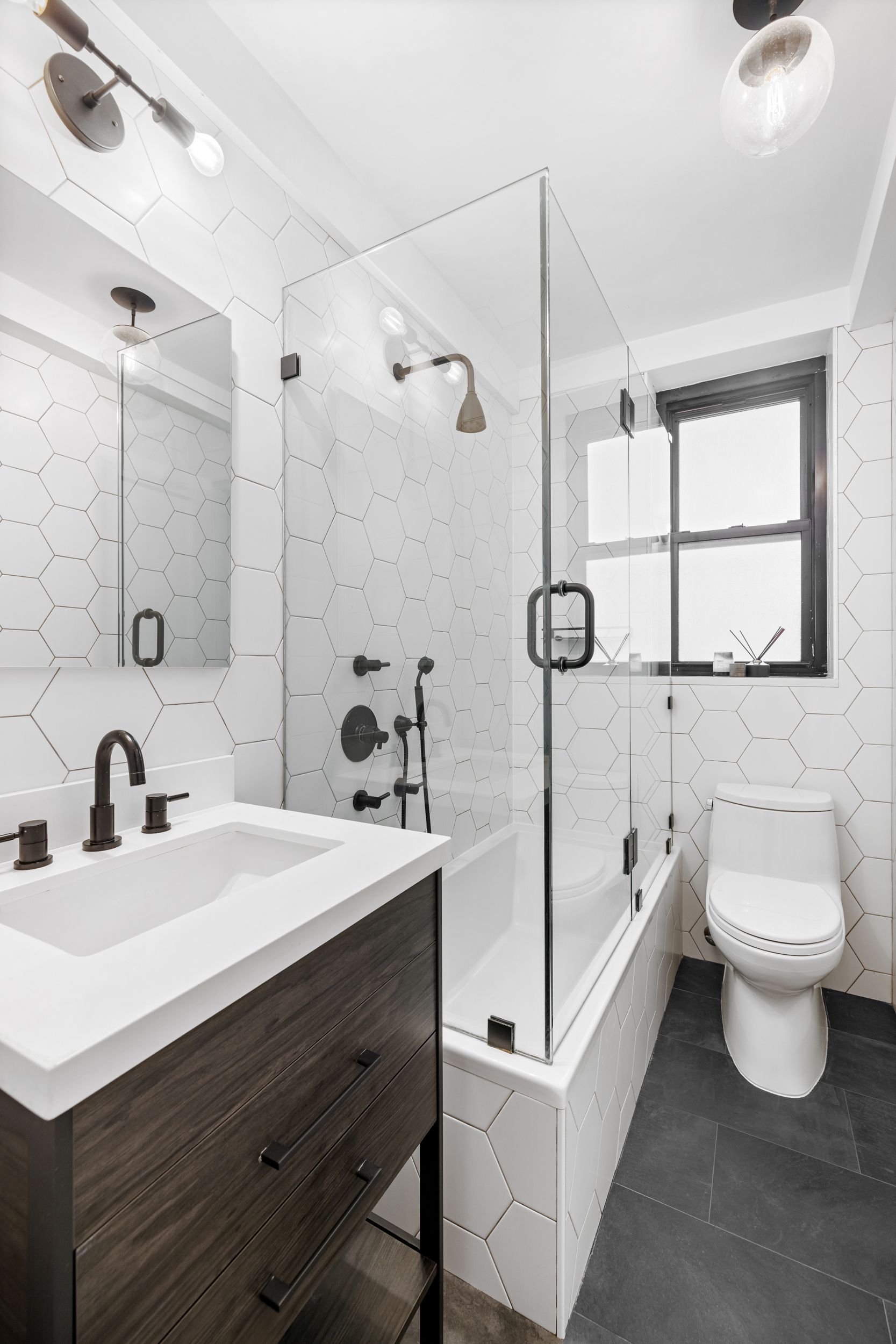 235 East 22nd Street, Unit 4T Manhattan, NY 10010 - Photo 7 of 15 a bathroom with a sink toilet a mirror and shower