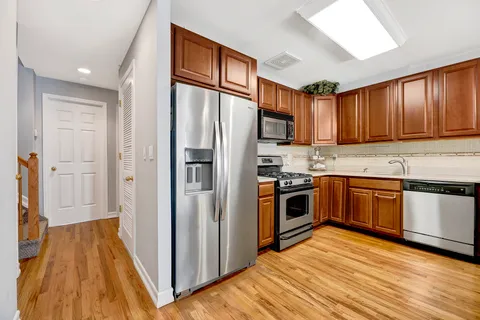 a kitchen with stainless steel appliances granite countertop a refrigerator a sink dishwasher and wooden cabinets with wooden floor