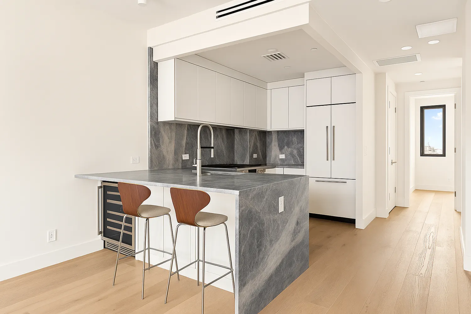 a kitchen with stainless steel appliances kitchen island granite countertop a refrigerator a stove a sink and white cabinets with wooden floor