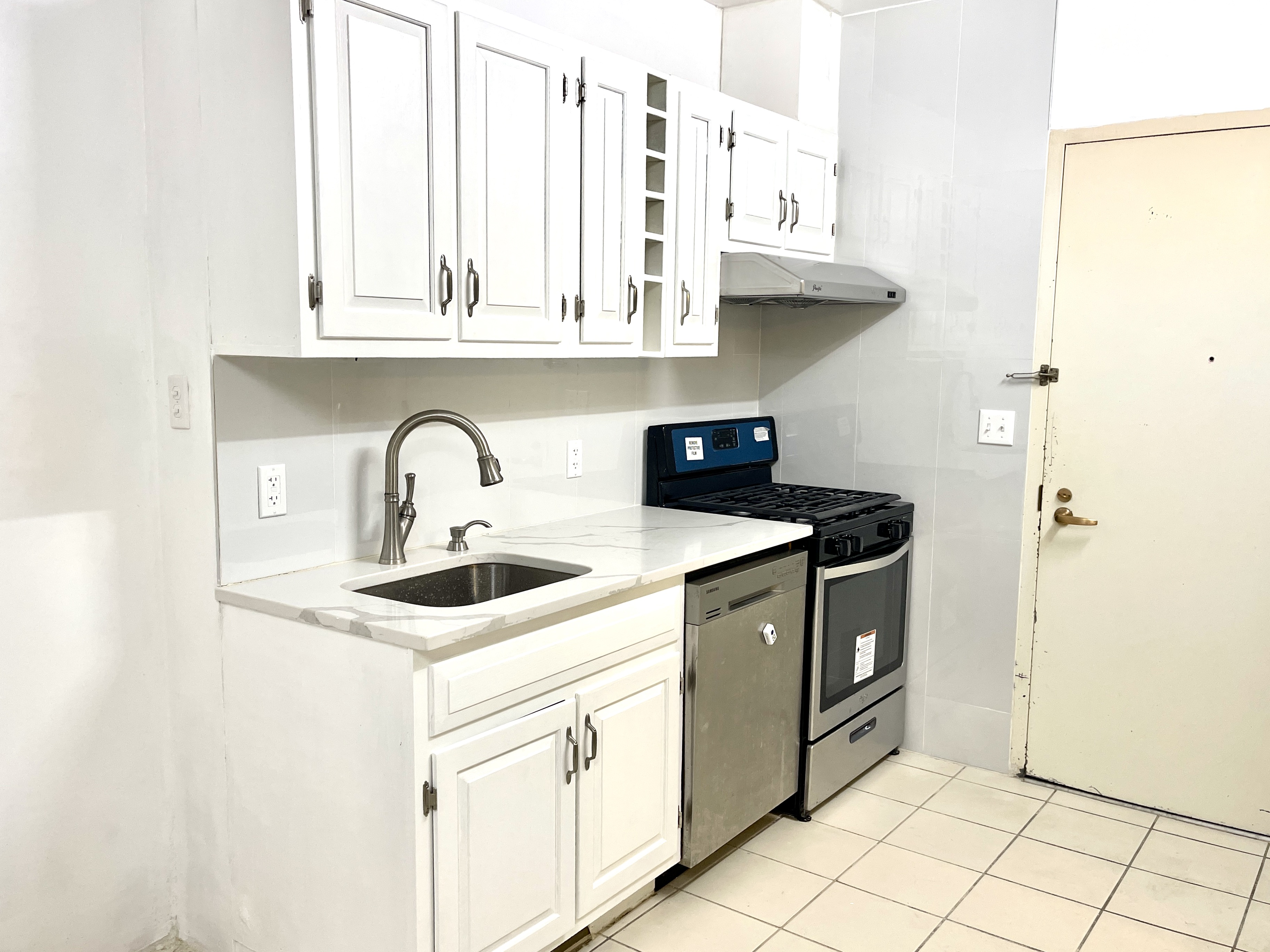 148A Madison Street, Unit 4 Manhattan, NY 10002 - Photo 3 of 13 a kitchen with stainless steel appliances granite countertop a sink and a white cabinets