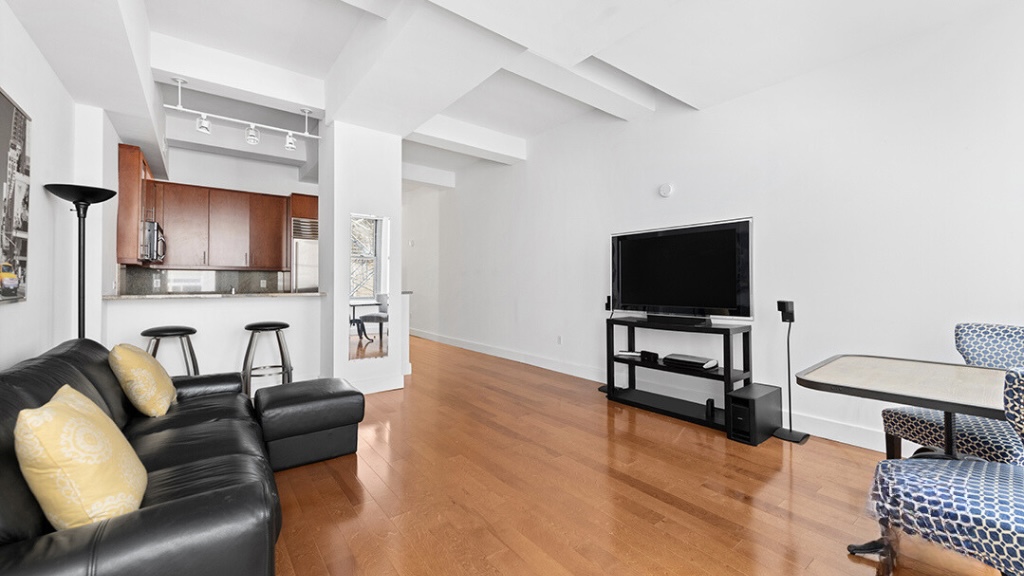 80 John Street, Unit 11E Manhattan, NY 10038 - Photo 2 of 9 a living room with furniture and a flat screen tv