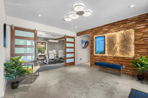 a living room with furniture potted plant and couches next to a large window