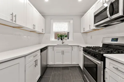 a kitchen with white cabinets stainless steel appliances and sink