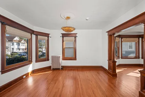 a view of an empty room with a window and wooden floor