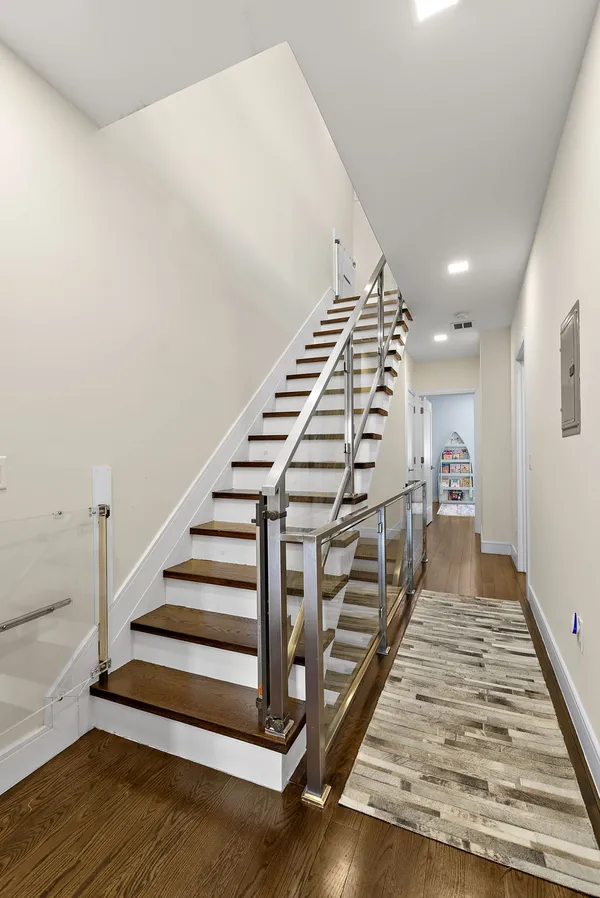 a view of a hallway with stairs and wooden floor