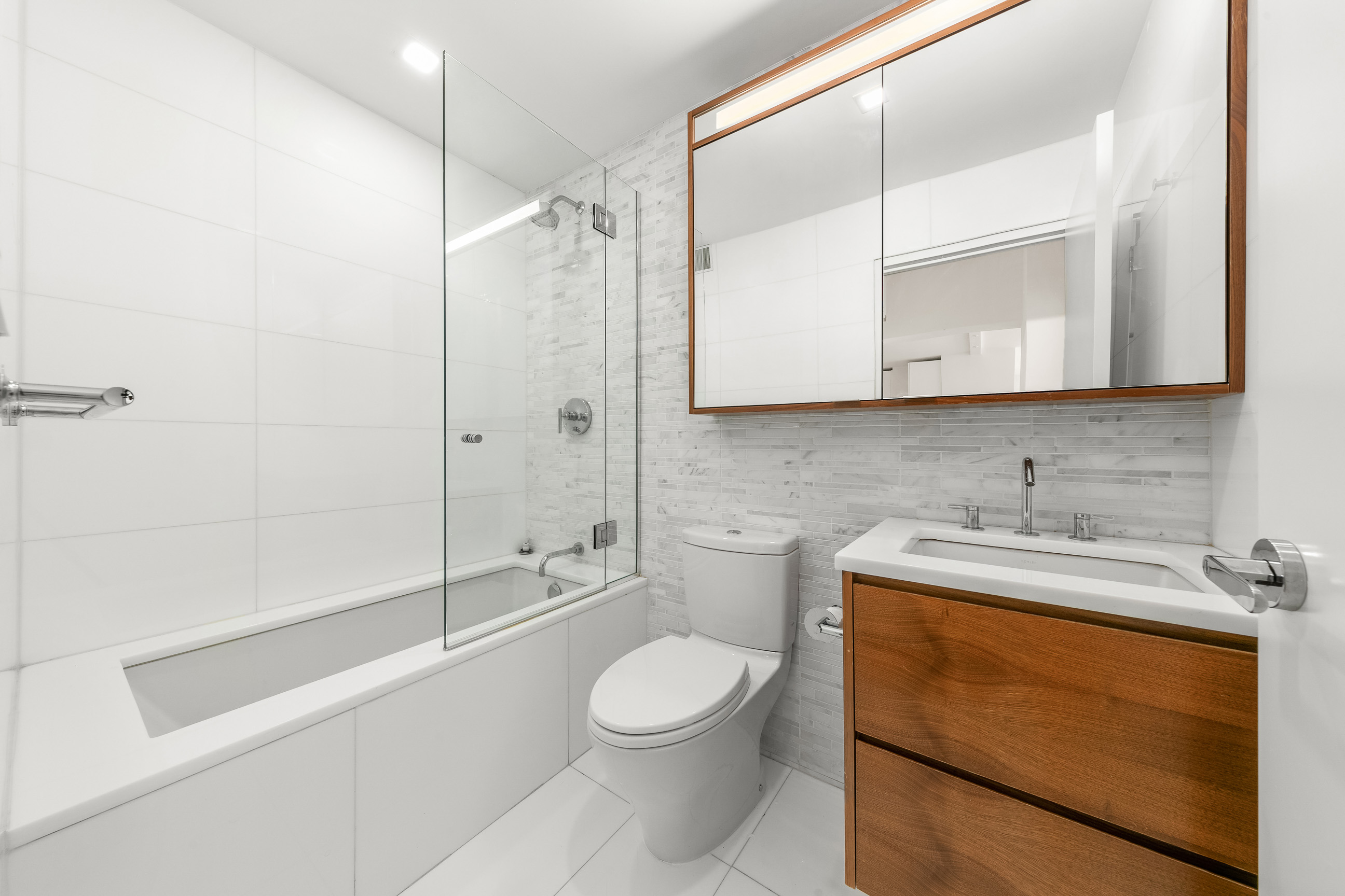 301 West 53rd Street, Unit 19K Manhattan, NY 10019 - Photo 6 of 8 a bathroom with a granite countertop sink toilet a mirror and shower