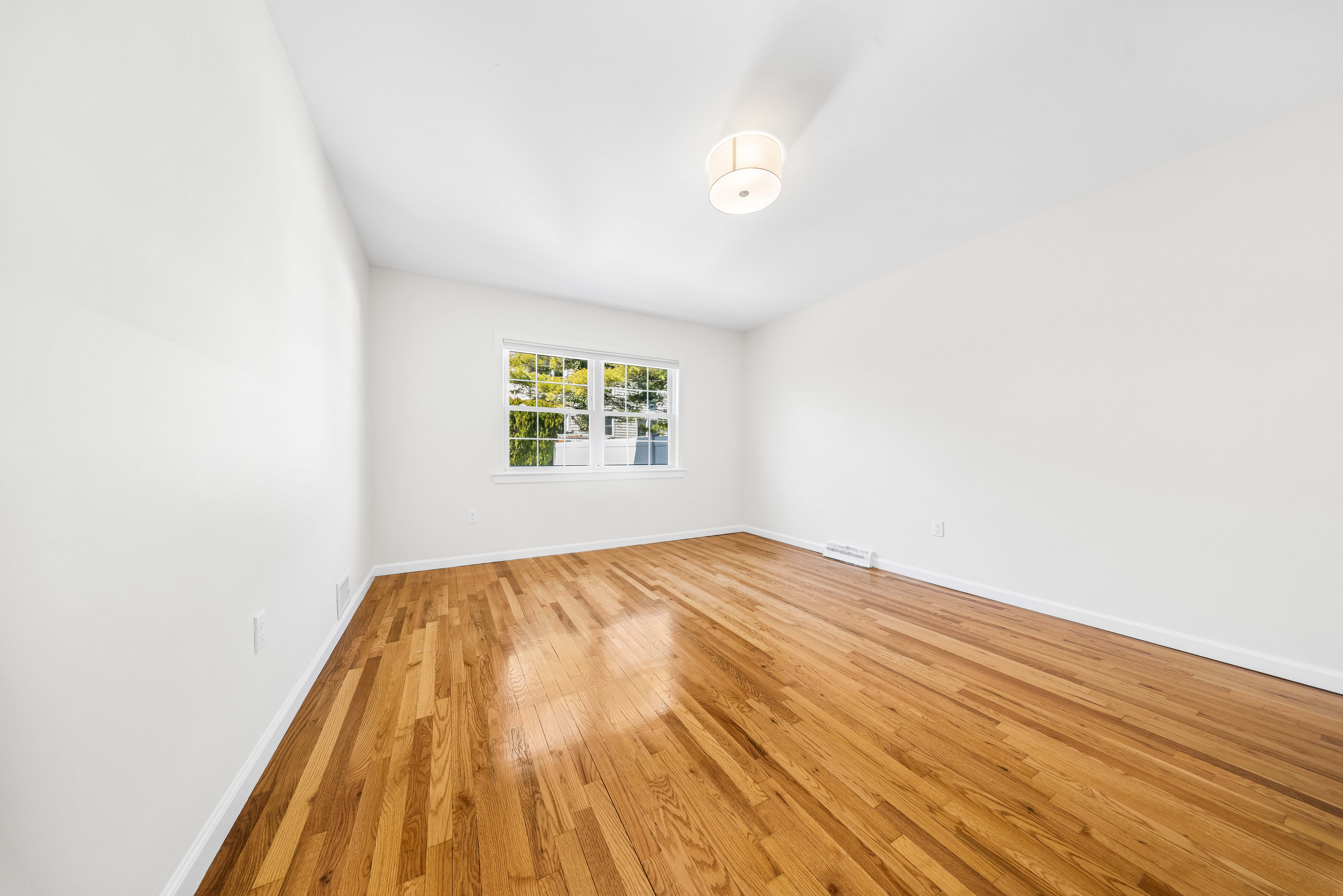15-80 209th Street, Unit 2 Queens, NY 11360 - Photo 10 of 21 a view of a room with wooden floor and a window