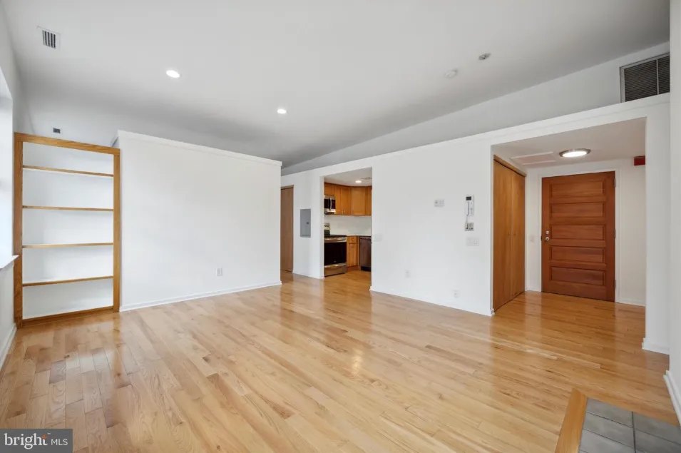 a view of an empty room with wooden floor and closet