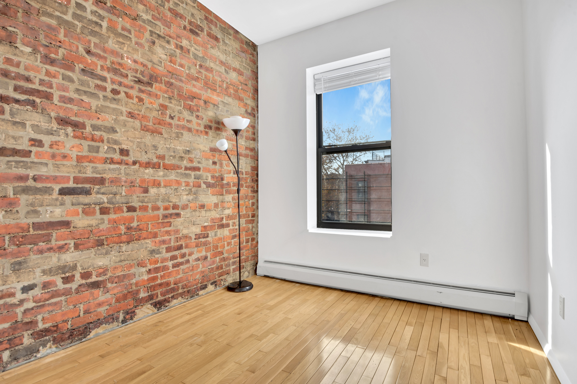 277 Nostrand Avenue, Unit 3A Brooklyn, NY 11216 - Photo 7 of 10 a view of an empty room with wooden floor and a window