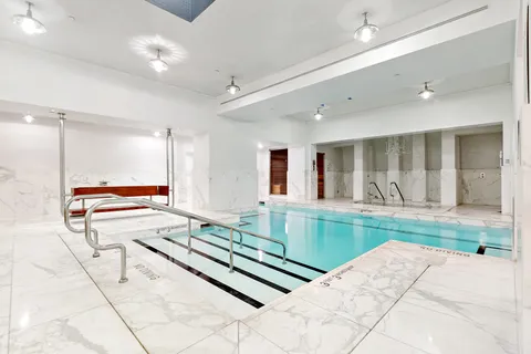 a large white kitchen with kitchen island a large window and a rug