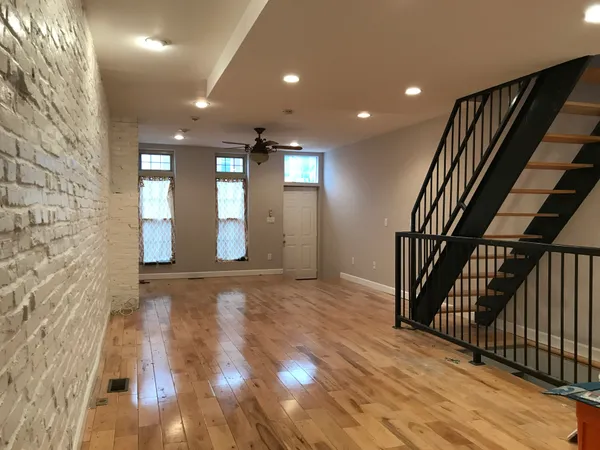 a view of an empty room with wooden floor and stairs