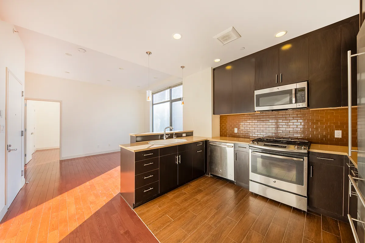 51-42 27th Street, Unit 6C Queens, NY 11101 - Photo 4 of 10 a large kitchen with stainless steel appliances granite countertop a stove and a sink