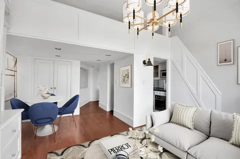 a living room with furniture or chandelier and a wooden floor