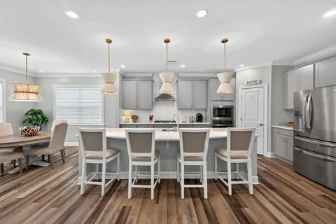 a kitchen with stainless steel appliances a dining table chairs and white cabinets