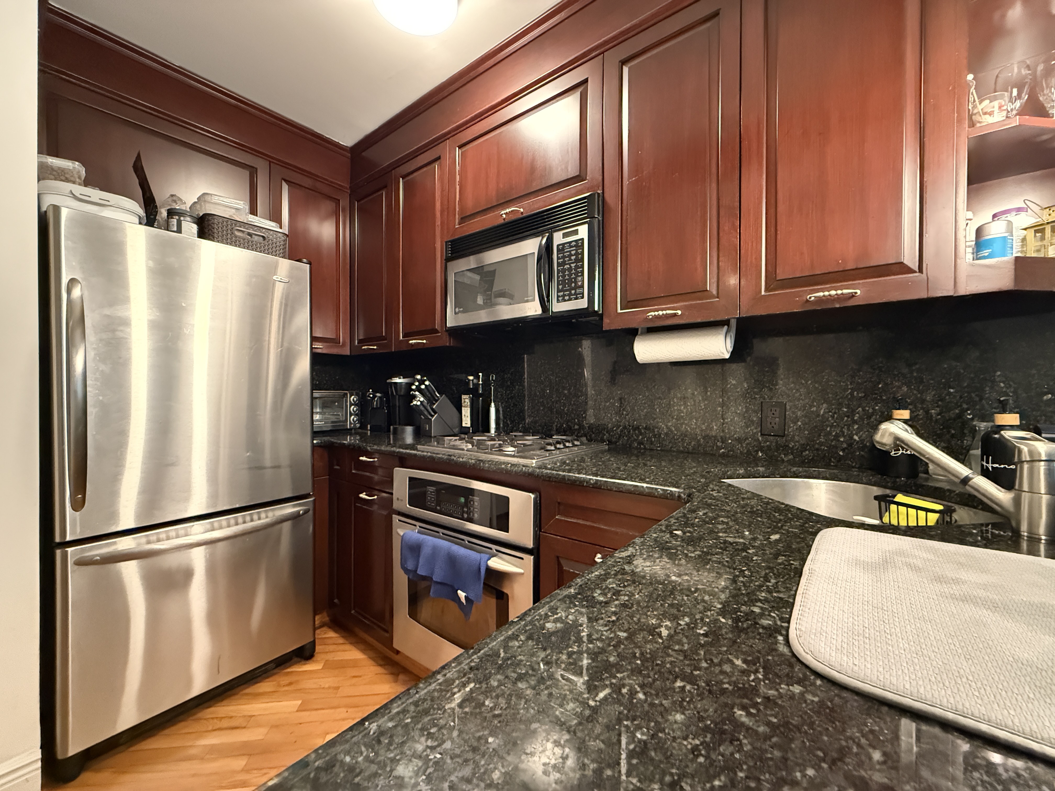 101 Prospect Park Southwest, Unit 3B Brooklyn, NY 11218 - Photo 9 of 23 a kitchen with stainless steel appliances granite countertop a refrigerator a stove and a sink with wooden cabinets