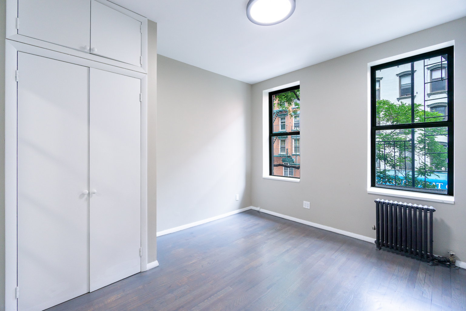 an empty room with wooden floor and windows