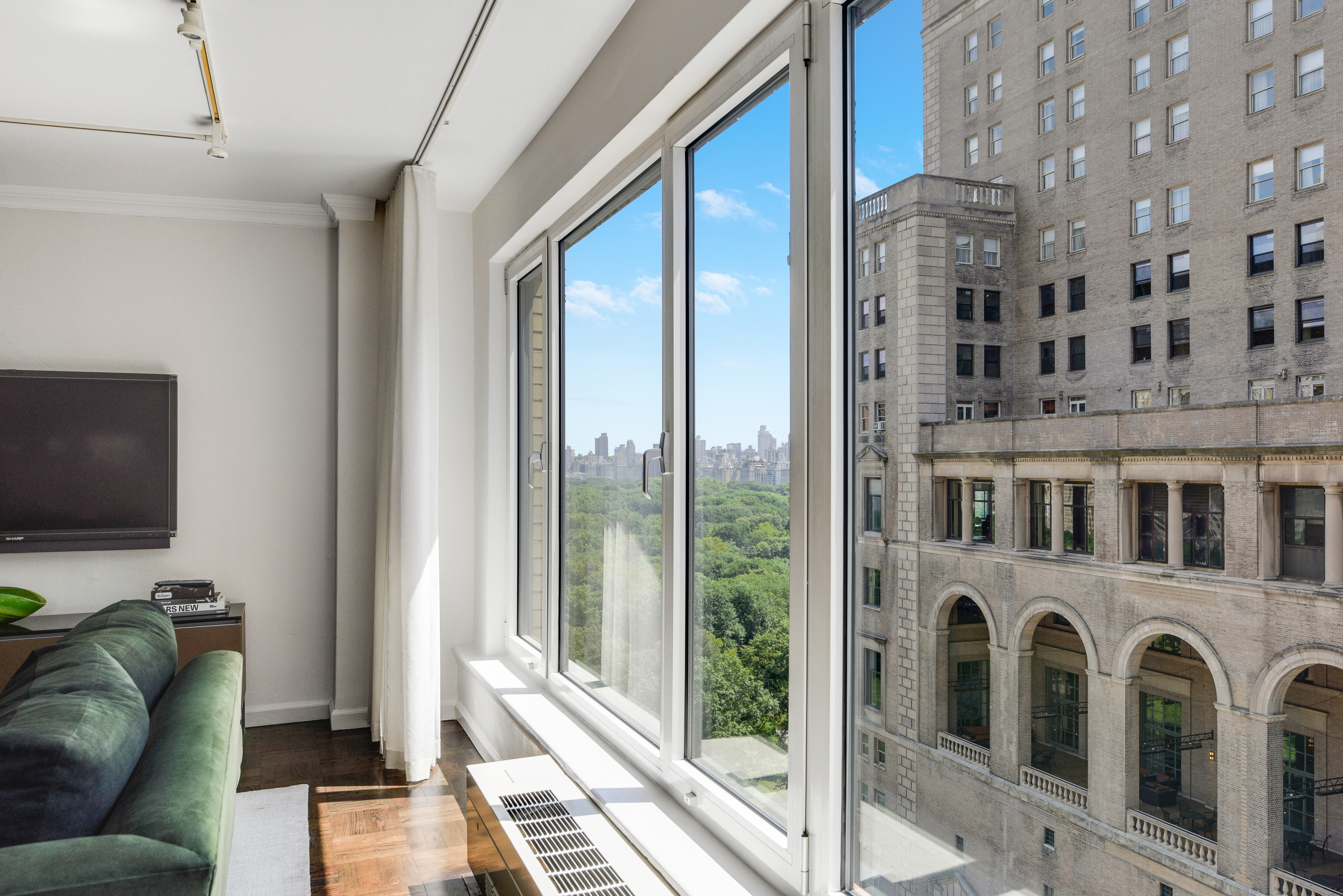 200 Central Park South, Unit 19J Manhattan, NY 10019 - Photo 7 of 12 a living room with furniture a flat screen tv and a floor to ceiling window