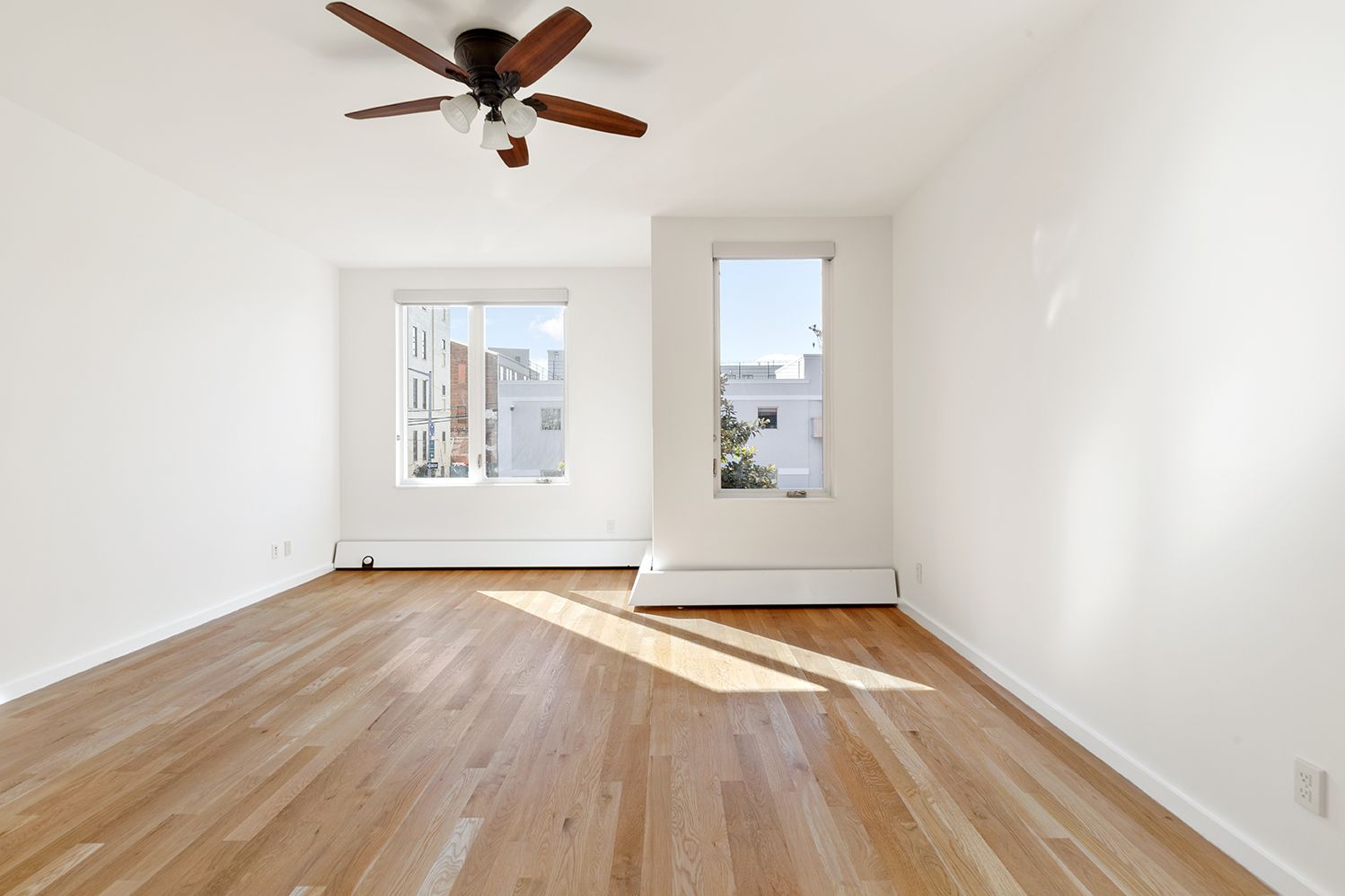 a view of empty room with wooden floor and fan