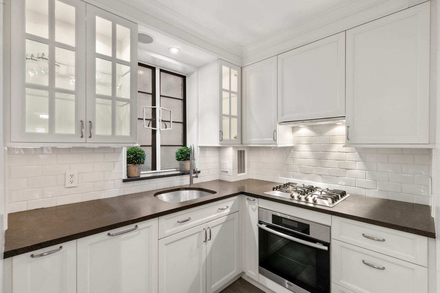 110 East 87th Street, Unit 2C Manhattan, NY 10128 - Photo 4 of 13 a kitchen with stainless steel appliances white cabinets and a stove top oven