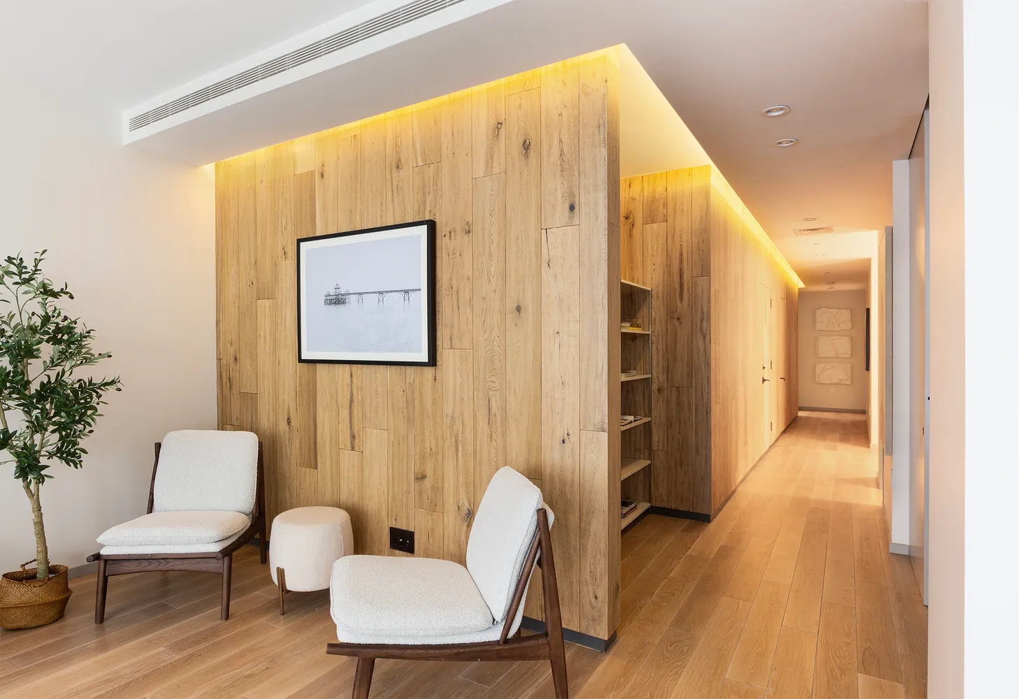 a view of a hallway with furniture and wooden floor