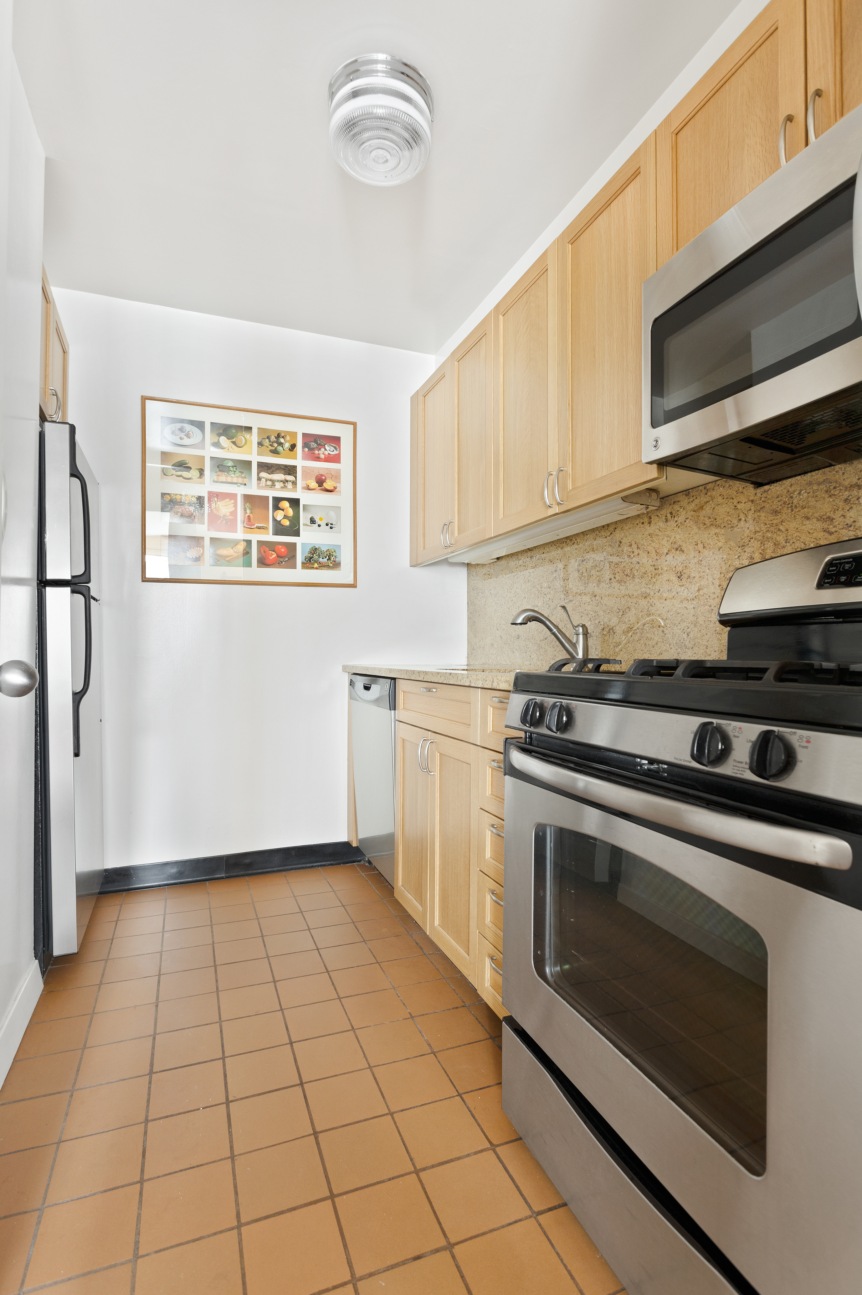 15 West 53rd Street, Unit 11H Manhattan, NY 10019 - Photo 7 of 11 a kitchen with a stove top oven cabinets and stainless steel appliances