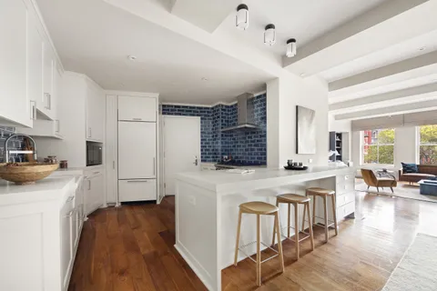 a kitchen with a stove a refrigerator a oven a sink dishwasher and white cabinets with wooden floor