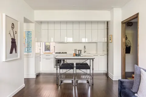 a kitchen with stainless steel appliances kitchen island wooden floors and white cabinets